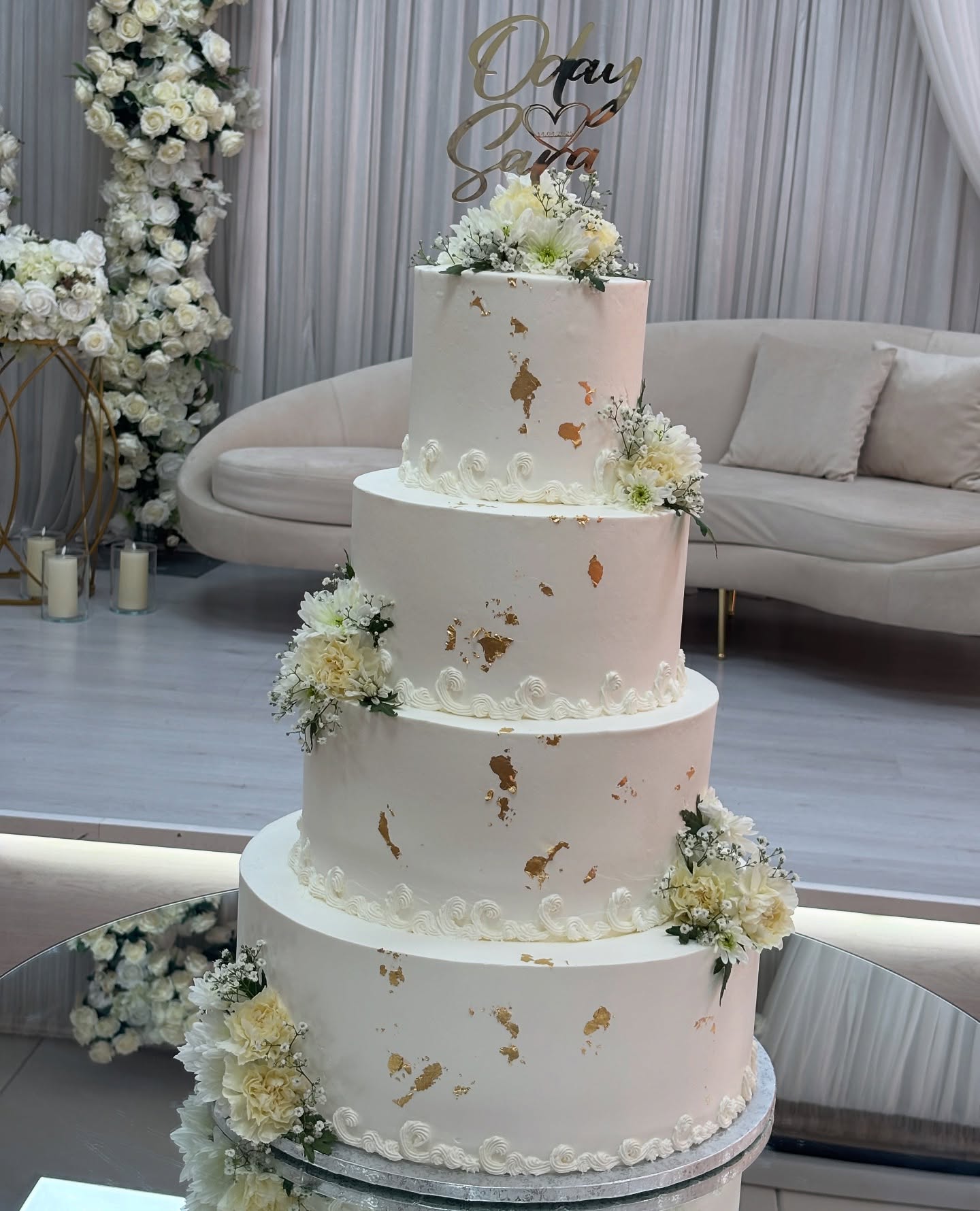 Bryllupskake i fire etasjer med bladgull og hvite blomster